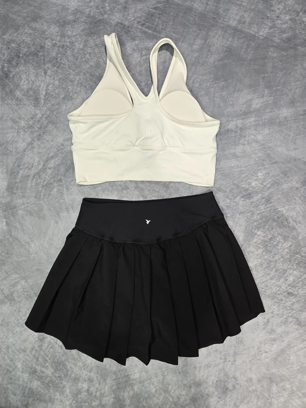ALO Yoga Wild Thing Bra paired with a black pleated skirt